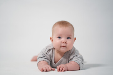 portrait of a baby on a white background. Baby lying on his stomach looking at the camera