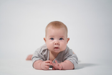 Fototapeta premium portrait of a baby on a white background. Baby lying on his stomach looking at the camera