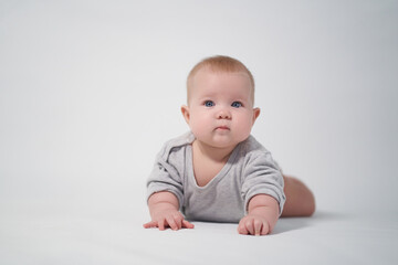 Portrait of a Baby in a gray jumpsuit, the photo was taken in a bright studio