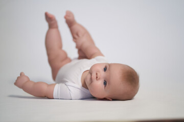 A newborn baby is trying to roll over on his stomach. photography on a light background