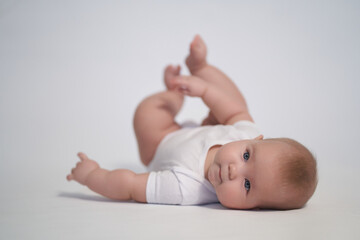 A newborn baby is trying to roll over on his stomach. photography on a light background