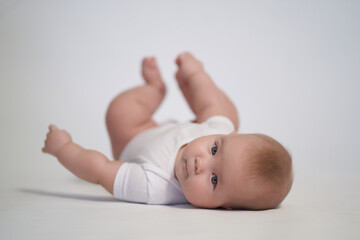 A newborn baby is trying to roll over on his stomach. photography on a light background