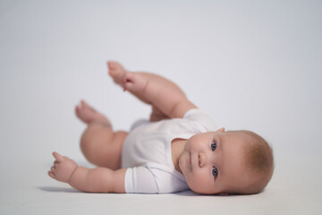 A newborn baby is trying to roll over on his stomach. photography on a light background