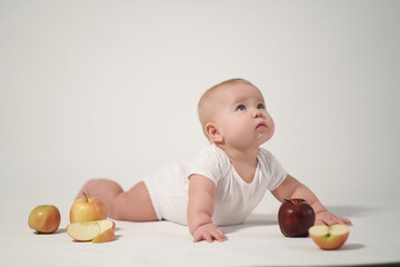 Newborn baby photo on a light background among apples