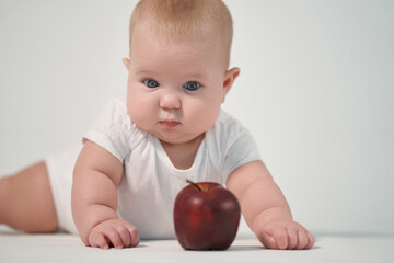 Newborn baby with red apple on white background