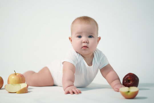 Newborn baby photo on a light background among apples
