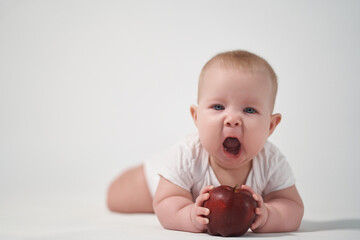 Baby 7 months old with a red apple in his hands