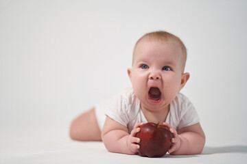 Baby 7 months old with a red apple in his hands