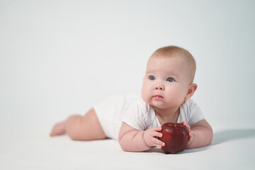 Baby 7 months old with a red apple in his hands. photography on a white background