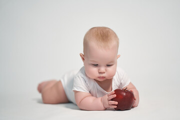 Baby 7 months old with a red apple in his hands. photography on a white background
