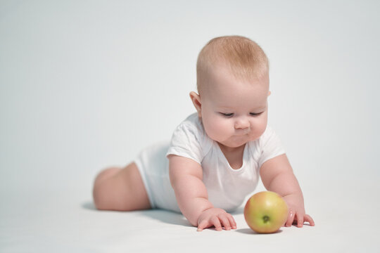 Baby 7 months old with an apple. photography on a white background