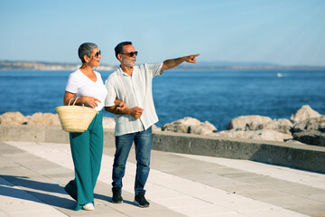 Mature Tourists Couple Pointing Finger Aside Looking At Sea Outdoors