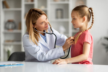 Female doctor checking lungs of little girl during medical checkup in clinic
