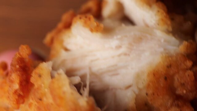 Girl's fingers tearing apart a piece of fried filet chicken nuggets. Macro, chicken nugget fibers