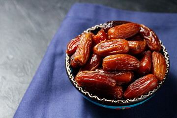Bowl of pitted dates on a blue linen napkin. Tasty sweet dried dates in bowl. Ramadan food