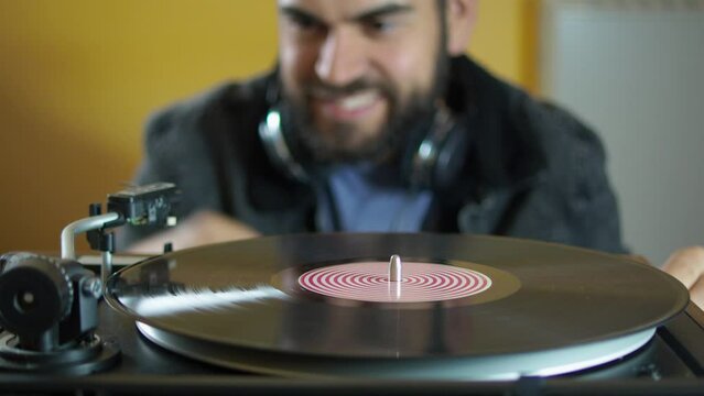 Young man using headphones while playing a vinyl record on a vintage turntable