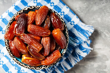 Pitted dates in bowl on a linen napkin. Close up of bowl with healthy snack - dried sweet dates. Healthy organic vegetarian food