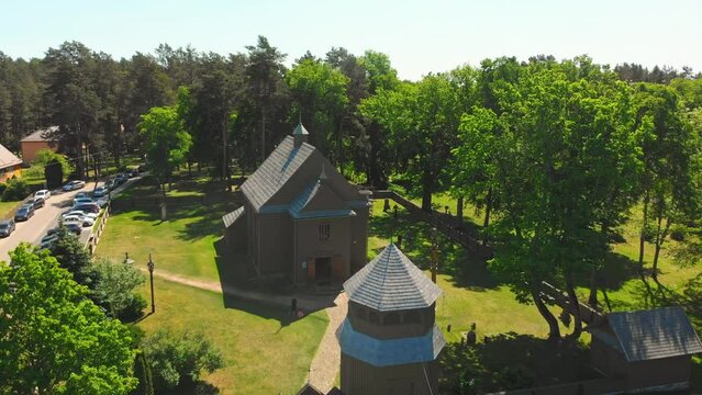 Aerial view Young lithuanians relax on sunday mass by St. Joseph Church in Paluse, Lithuania. Stave Churches in Europe. Old heritage sites. Walls formed by vertical wooden boards.