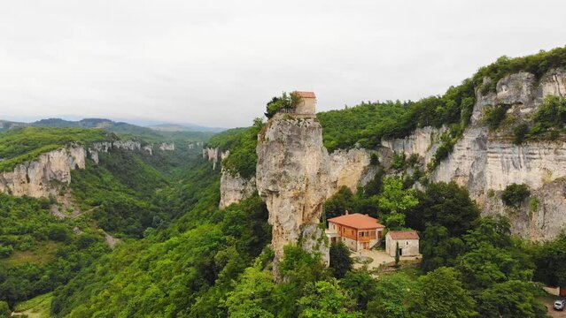 Aerial spin around Katskhi pillar. Man's monastery near the village of Katskhi. The orthodox church and the abbot cell on a rocky cliff. Imereti, Georgian meteora monastery concept