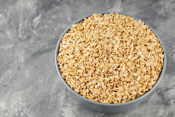Dry oat flakes in bowl on a gray background. Oat groats flattened into flakes. Top view. Copy space