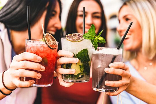 Group of happy friends toasting and drinking fancy cocktails at bar terrace-Three Young girls drink mojito and clinking glass together at pub enjoying happy hour at summer party- Life Style concept 
