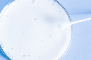 Washing agent foam in a Petri dish. On a blue background.