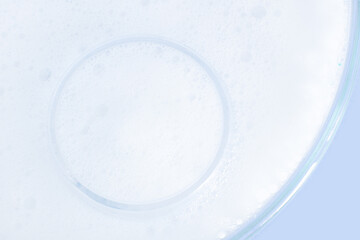 Washing agent foam in a Petri dish. On a blue background.