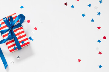 Fototapeta premium 4th of July, USA Presidents Day, Independence Day, US election concept. Gift striped box with bow, star confetti on white background. Flat lay, top view, copy space, banner