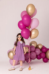 Fototapeta na wymiar People, joy, fun and happiness concept. Relaxed happy birthday little girl celebrating cheerful, smiling happily, posing for picture, holding colorful helium balloons