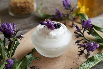 Homemade comfrey root ointment with blooming plant