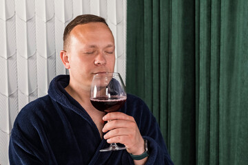 Portrait A homebody man in a blue bathrobe. A middle aged man with a glass of wine relaxing after work.