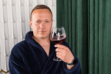Portrait A homebody man in a blue bathrobe. A middle aged man with a glass of wine relaxing after work.
