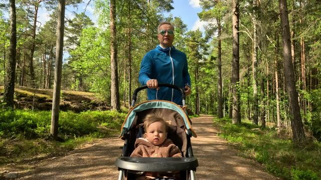 Male runner jogging with a pram baby carriage along an empty alley in a Park in Finland.
