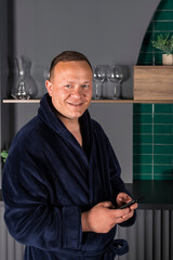 Portrait A homebody man in a blue bathrobe. A middle aged businessman relaxing at home and using phone