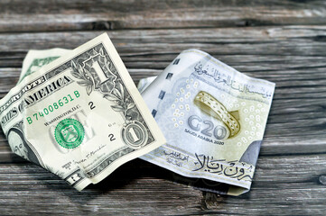 Wrinkled and crumpled Saudi Arabia money of 20 SAR twenty riyals and 1 one American dollar cash...