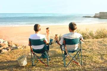 Senior Couple Sitting In Chairs Drinking Coffee Near Sea Outside