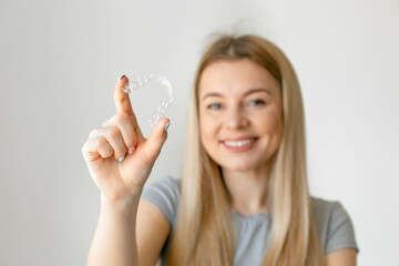 Smiling woman demonstrates mouth guards for bite alignment. The girl approves of the plastic...