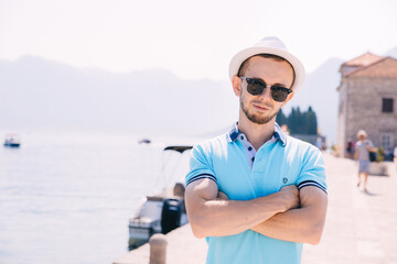 Fototapeta na wymiar Handsome man wearing hat near marina with yachts. Portrait man with sea port background with copy space