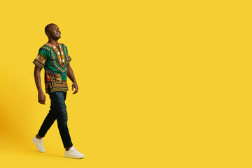 Happy mature black man walking towards copy space, yellow background