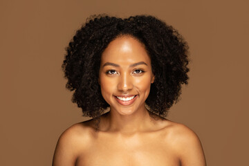 Attractive black woman with bushy hair posing naked on brown