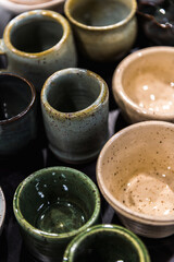 Top view flay lay composition of table full of different colours shapes and sizes handmade speckled pottery ceramics cups bowls