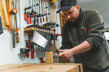 Carpenter using Japanese saw to cut wood in shop hardworking focused man at work. High quality photo