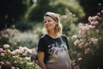 Fototapeta premium Portrait of a beautiful pregnant woman in the garden with pink flowers