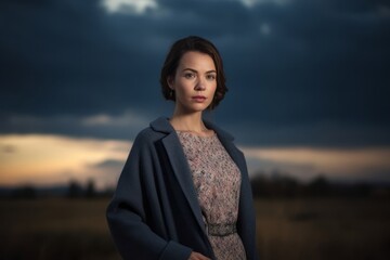 Young beautiful woman in a blue coat in the field at sunset.