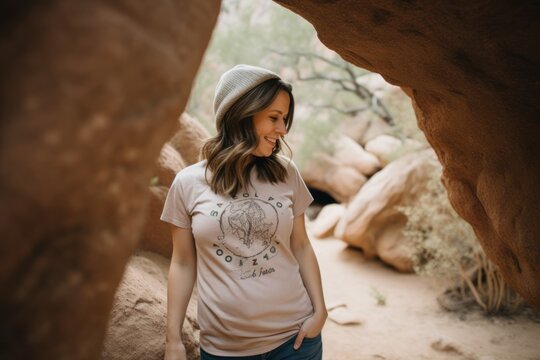 Lifestyle portrait photography of a cheerful pregnant woman in her 30s that is wearing a fun graphic tee against a rock formation or cliff background . Generative AI