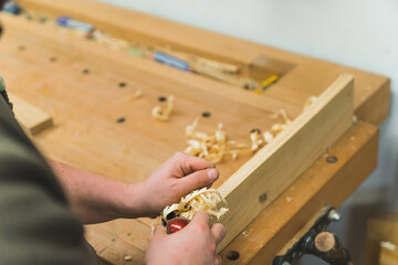 carpenter working in his workshop and using a jack plane for wood, closeup shot. High quality photo