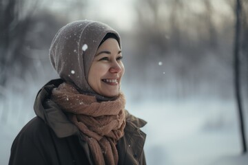 Medium shot portrait photography of a grinning pregnant woman in her 40s that is wearing hijab against a snowy landscape background . Generative AI