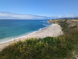 azure sky and turquoise Pacific waters with dreamy marshmallow clouds over coastal cliffs