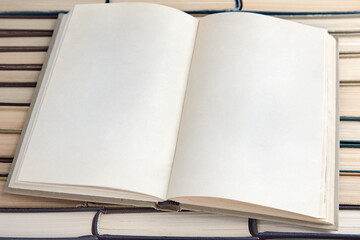 Open book diary with blank pages lies against the backdrop of shabby books lined upside down