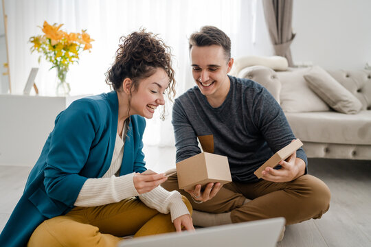 man hold and read greeting card while holding and opening presents gift box at home together with his girlfriend while sitting on the floor happy smile copy space real people caucasian adult